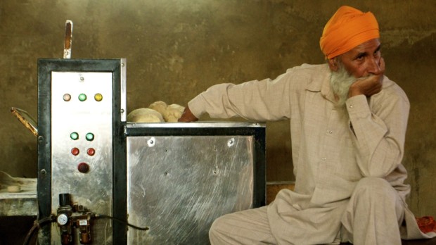 A man takes a break from putting dough in the automatic roti machine. The machine can produce about 25,000 rotis per hour. Photo by Jenna Belhumeur.