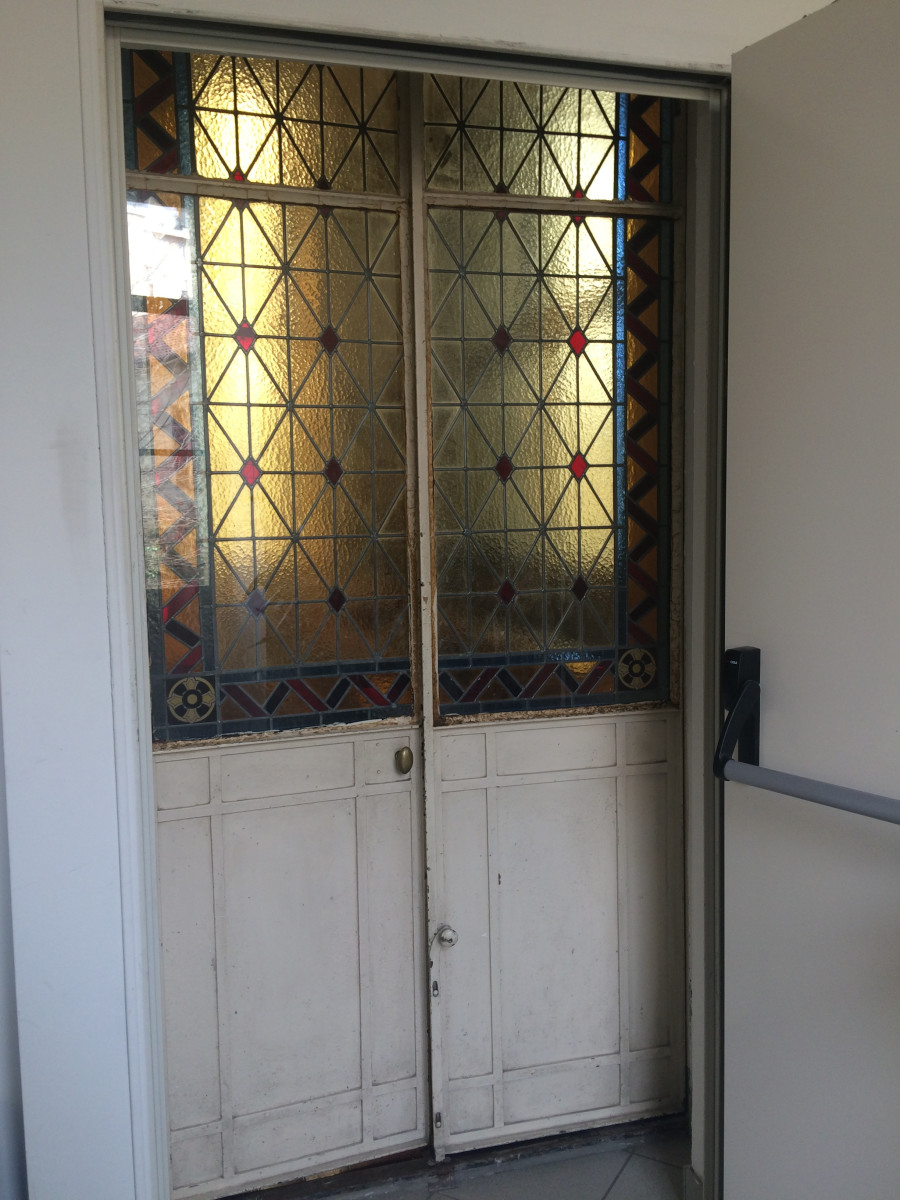 Doors to a classroom within Catholic Migrant Services building, located in Turin, Italy, reflect the stained glass usually found in cathedrals, creating a spiritual entrance into a place of learning.