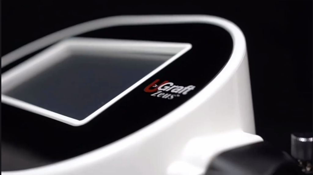 Close-up view of a UGraft Zeus device against a dark background.