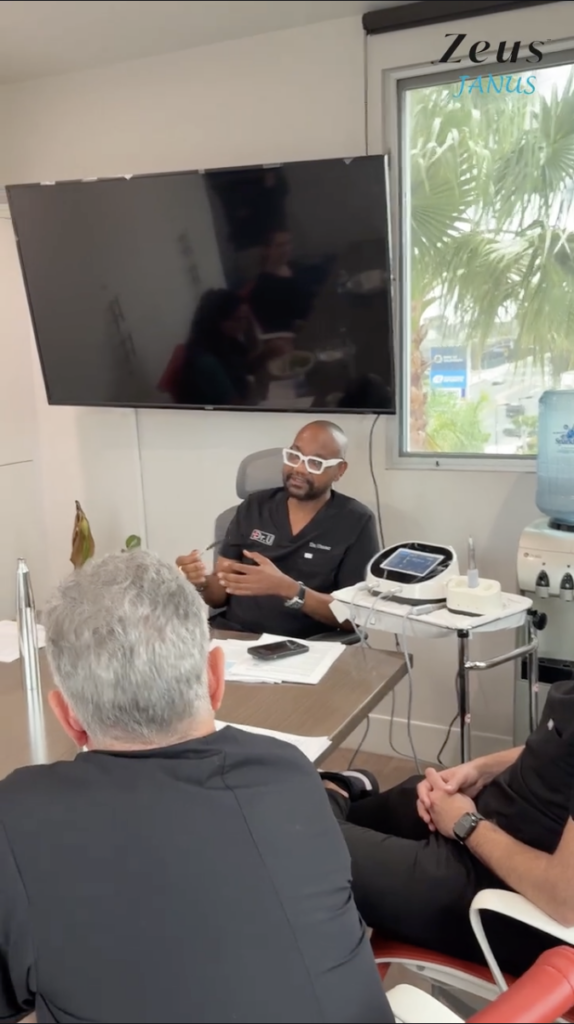 Dr. Sanusi Umar seated at a table speaking with visiting physicians in a clinical training room.