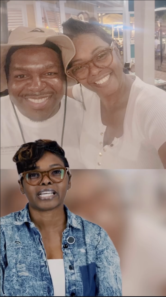 A woman in glasses and a blue denim jacket speaking to camera, with a photograph of two smiling people above her.