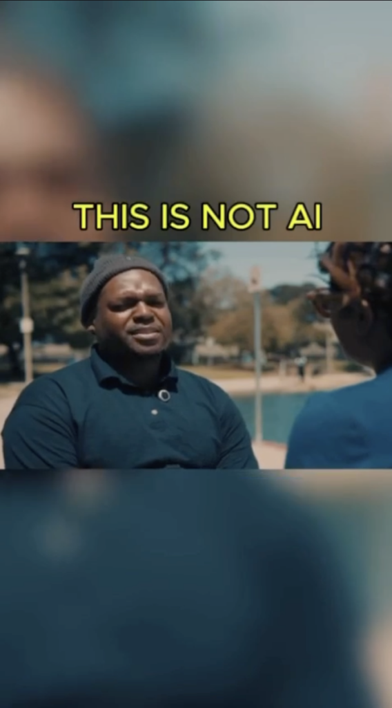 A man in a dark polo and knit cap speaking with another person outdoors, with the words This Is Not AI above.