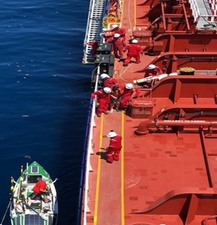 A reddish tanker, with their boat beside