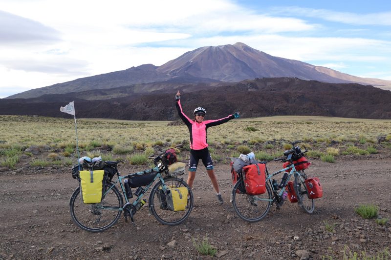 Aurelie stands with the bikes in front of a volcano