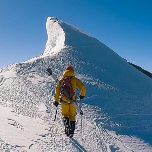 Bartek Ziemski walks to Dhaulagiri's snowy summit carrying the skis on his back.