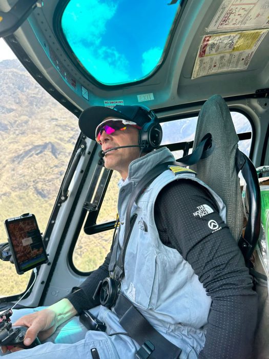 Simone inside the helicopter, looking up, with sunglasses, cap and headphones.