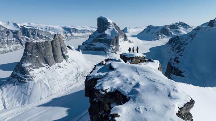 Three small figures at the top of a frozen arctic mountain