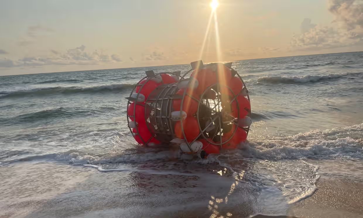 a hamster wheel vessel resting on a beach