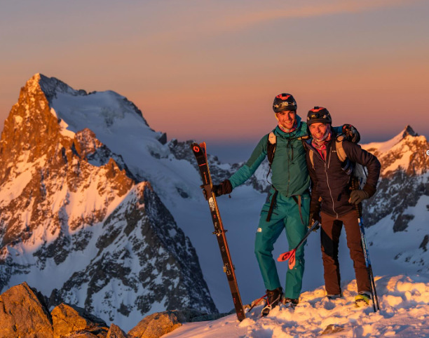 The skiers on a summit at sunset.