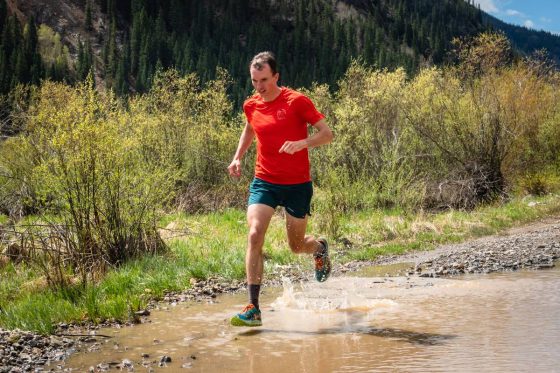 Runner wearing trail shoes in a mudding puddle