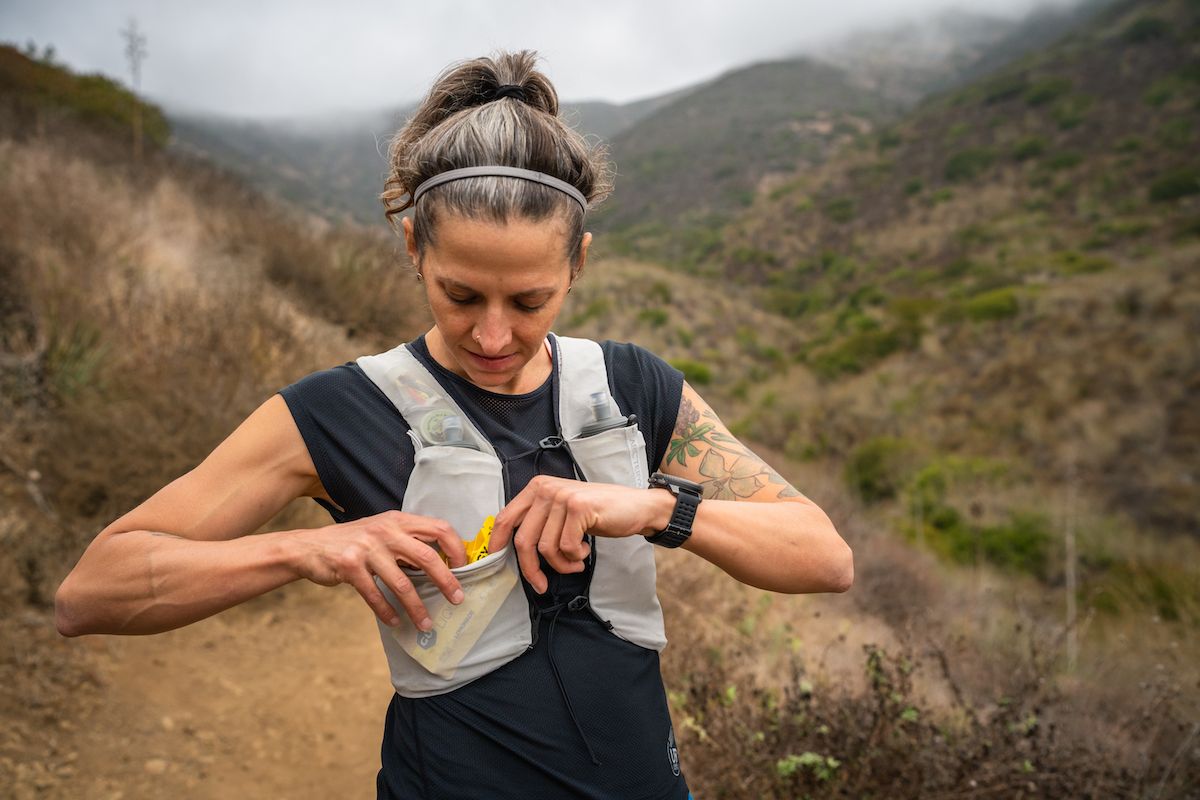 Best Running Vest - runner putting gel in pocket of running vest on trail
