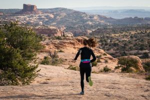 Best Running Belt - runner wearing Nathan 5K Waist Belt while running on desert trail