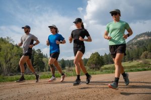 Best Road-to-Trail Shoes - four runners on sunny gravel road in mountains