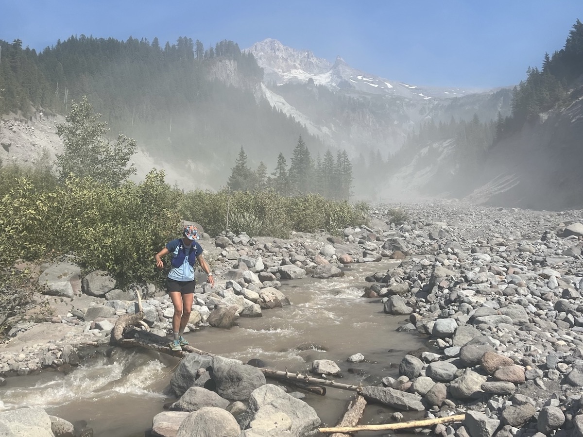 Best Running Hats - runner in Territory Run Co. Long Haul Cap crossing mountain stream