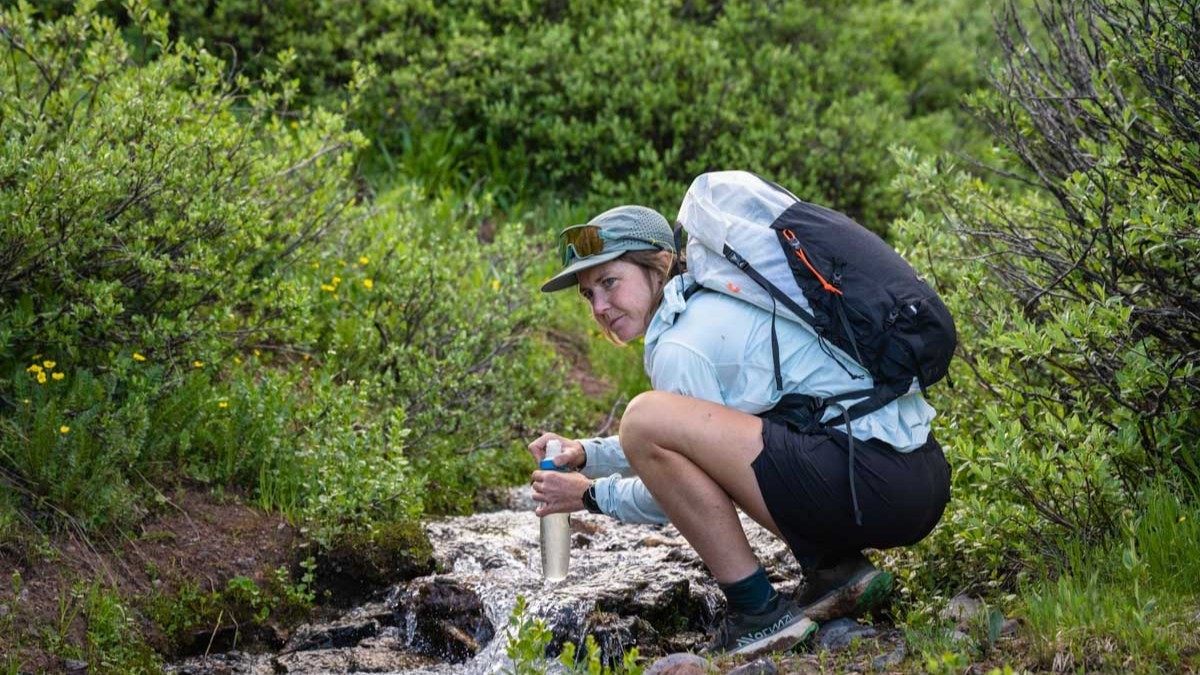 Best Water Filter for Trail Running - runner filtering water from stream