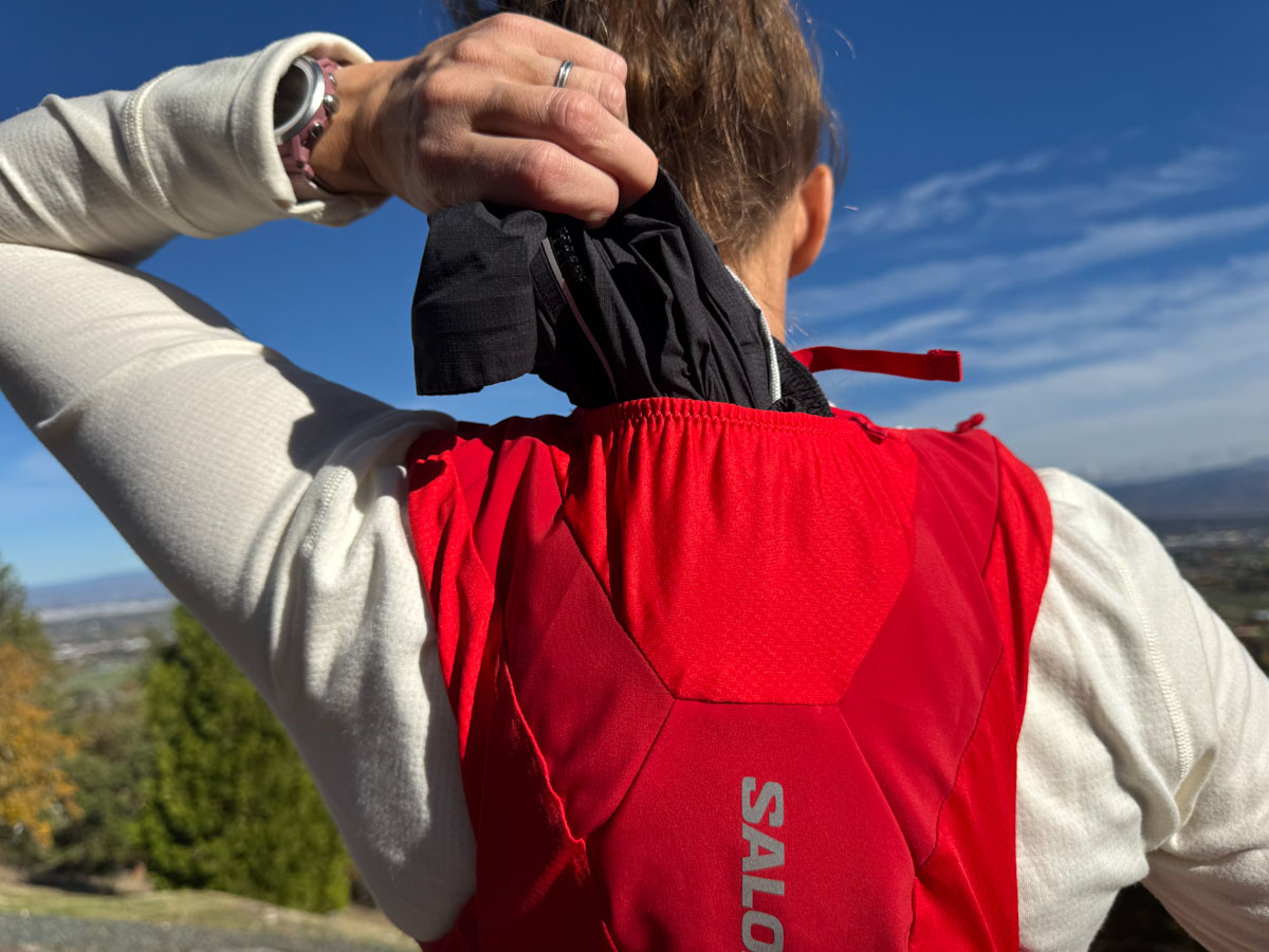 Person outside wearing a hydration pack viewed from rear - close up of top of main rear pocket