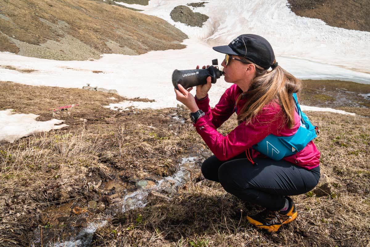 Best Water Filter for Trail Running - runner using the LifeStraw Peak Series Collapsible Squeeze 650 ml Bottle with Filter in mountain stream