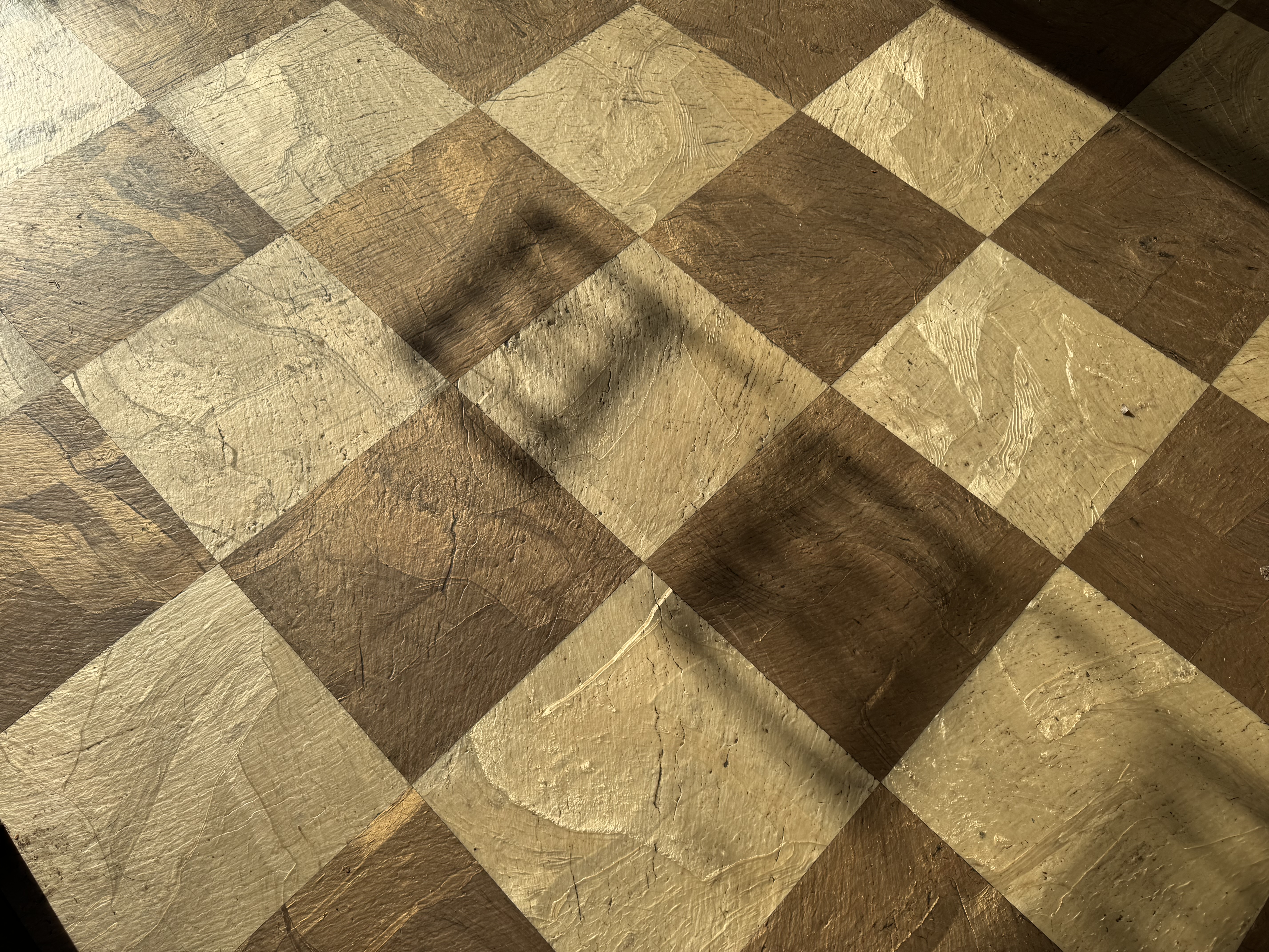 Tiled floor of a coffee shop, with the shadow of a window sign.