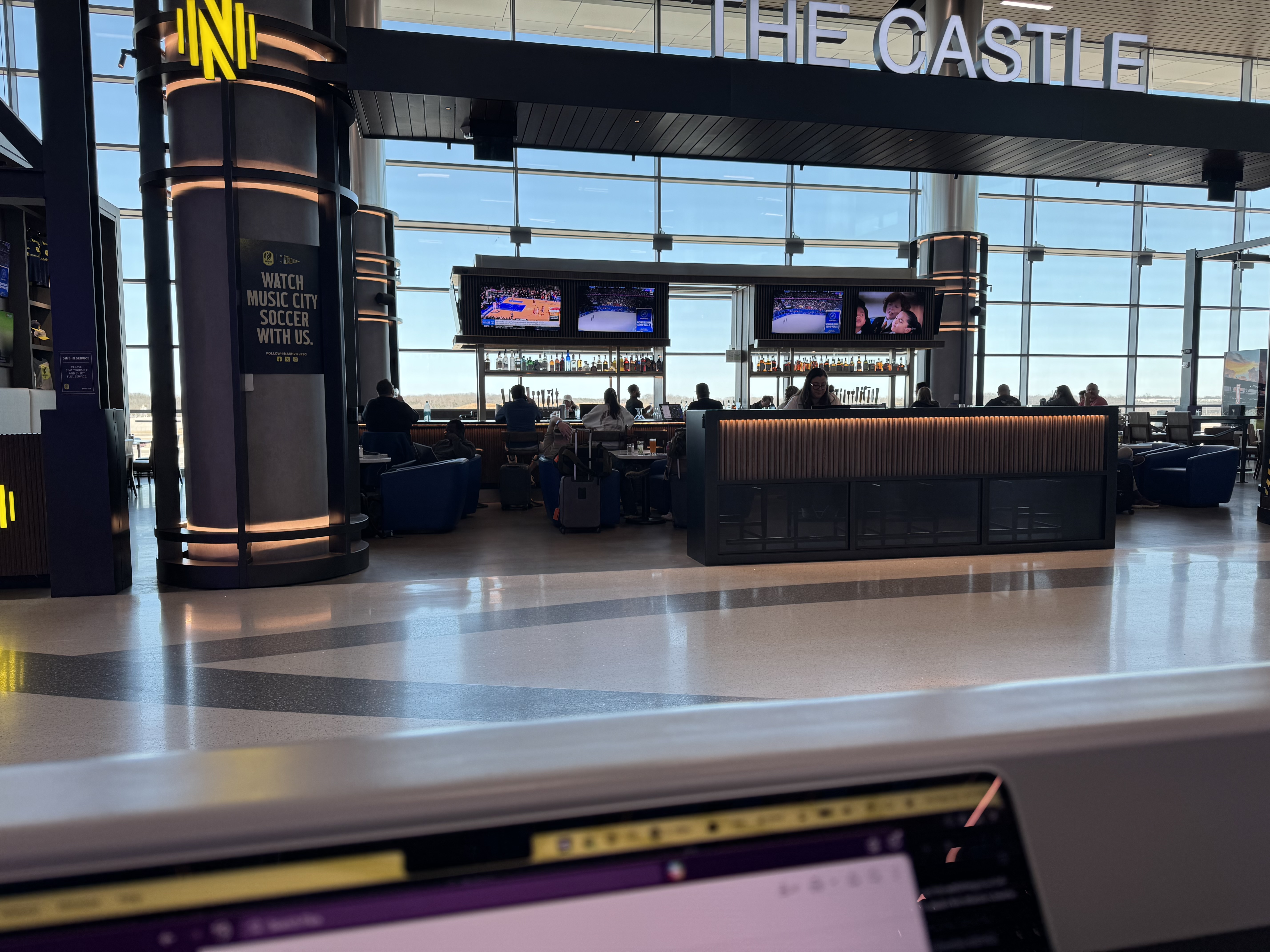 Olympic speed skating on a far off television at an airport bar.