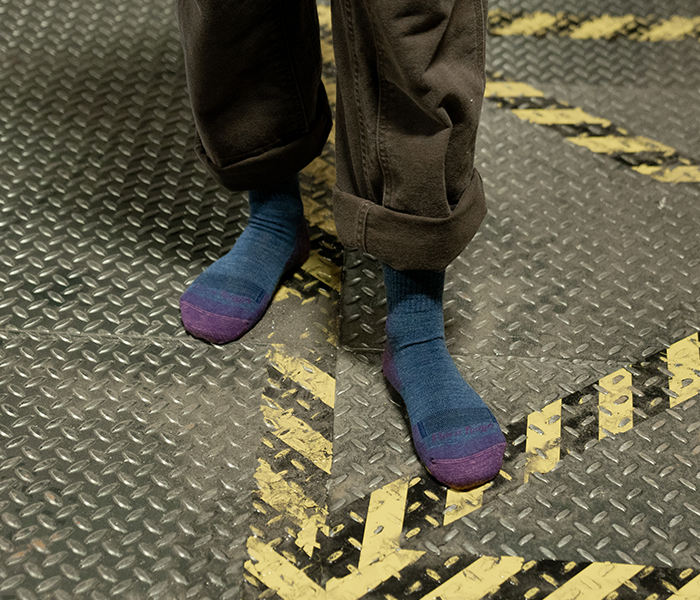 Someone stands in Darn Tough socks on a metallic diamond plated floor