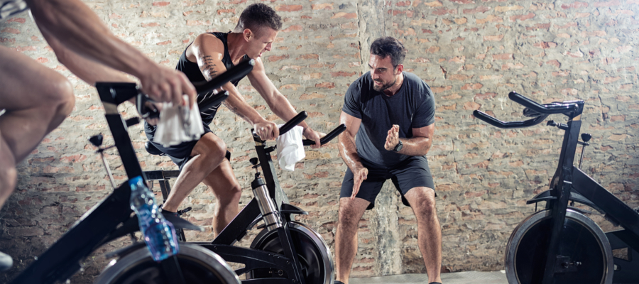 Cardio-Bikes personal trainer encourages student on spinning bike