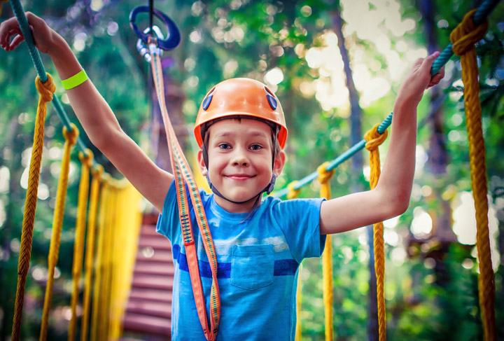 a caucasian boy on a obstacle course in a forest