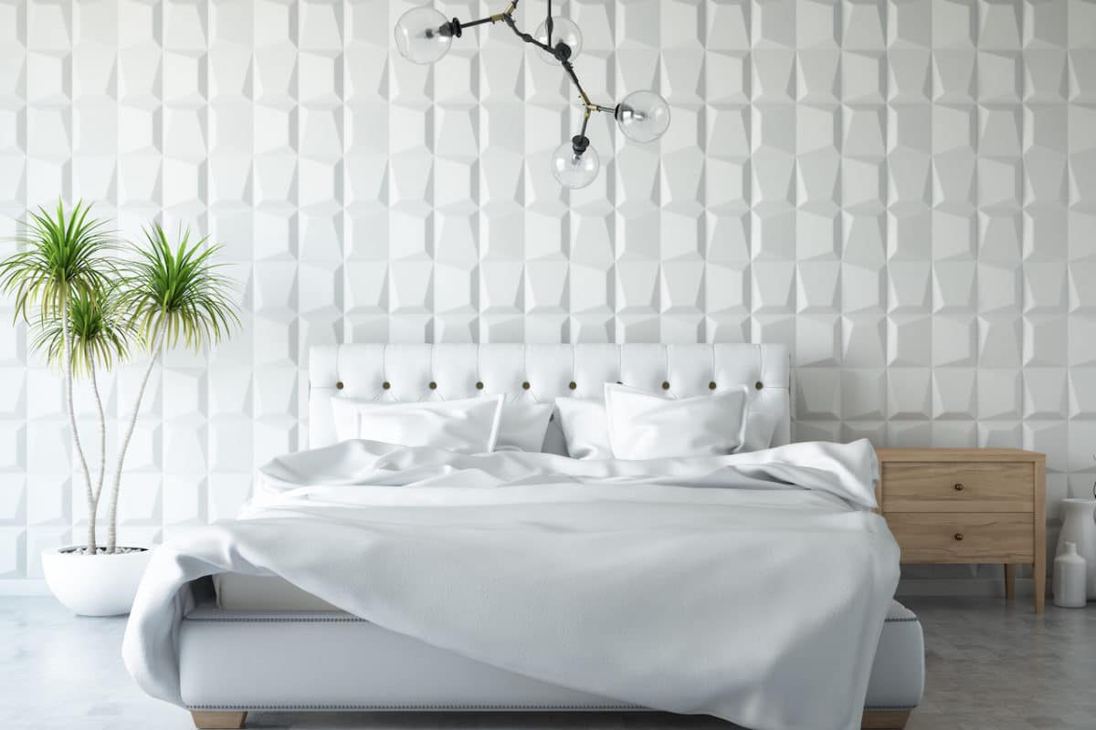 white bed in white room with green potted plant next to it