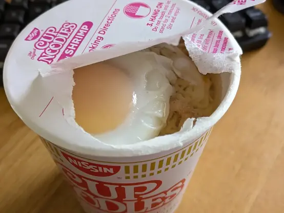 アメリカ版カップヌードルの敗れた蓋から半熟の卵が見えている