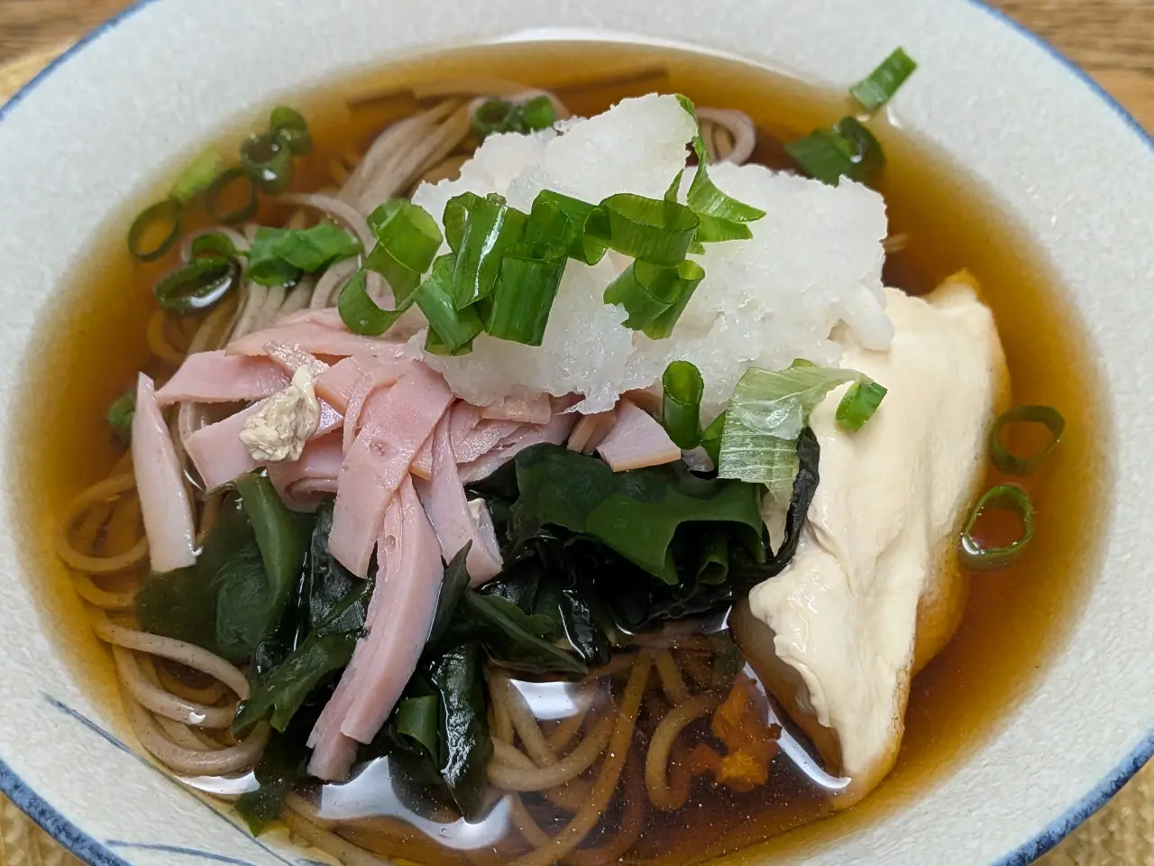 ハム、卵、大根おろし、ワカメ、ネギの乗った温かい蕎麦