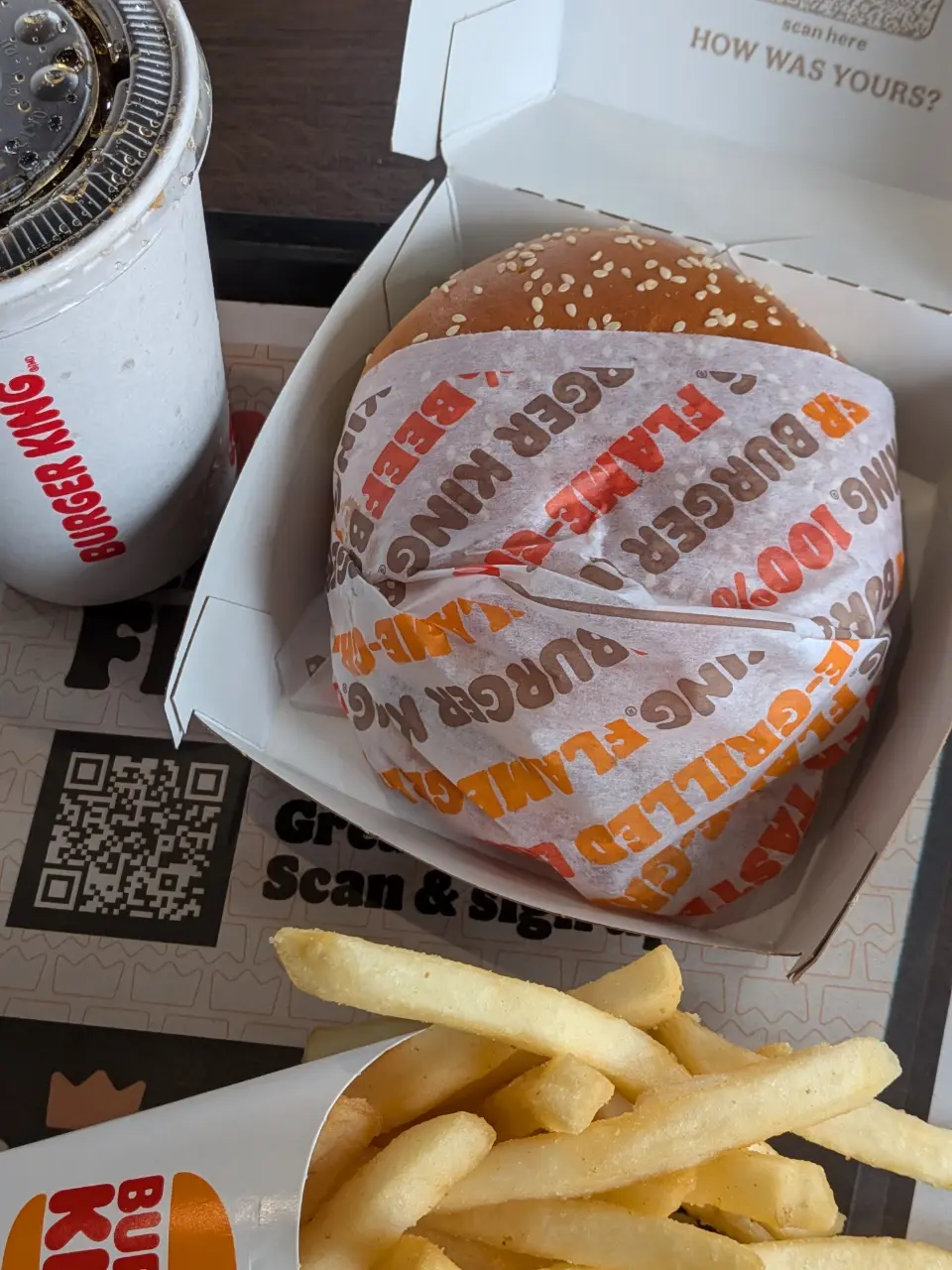 箱に収められたハンバーガー、フライドポテト、飲み物の紙コップの写真