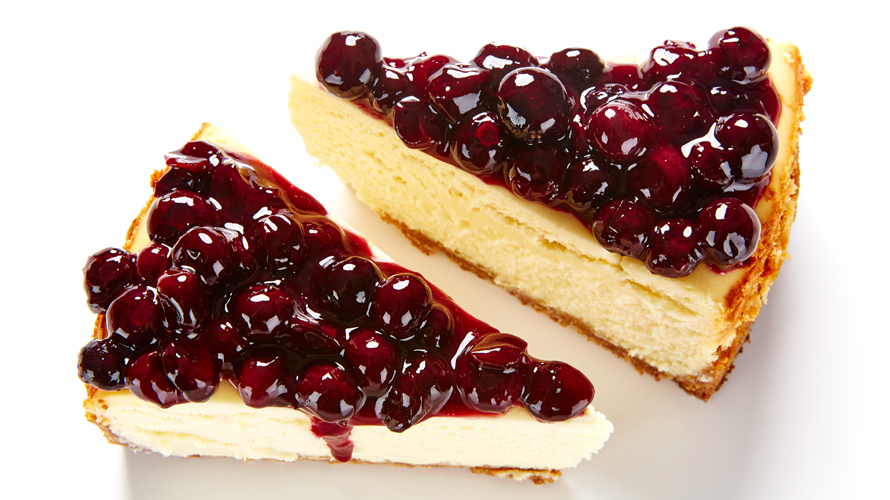 A piece of blueberry cheesecake with a buttery and golden graham cracker crust topped with a silky, scrumptious cheesecake filling and a sweet blueberry sauce.