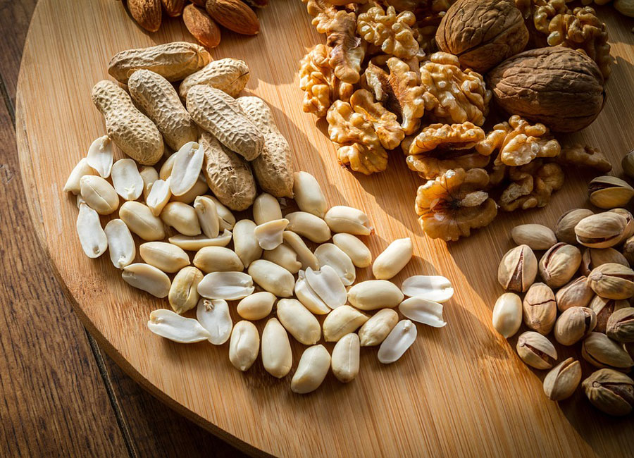 An assortment of nuts on a wooden cutting board.