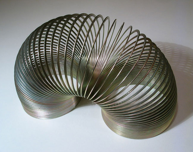 A steel slinky standing on both ends.