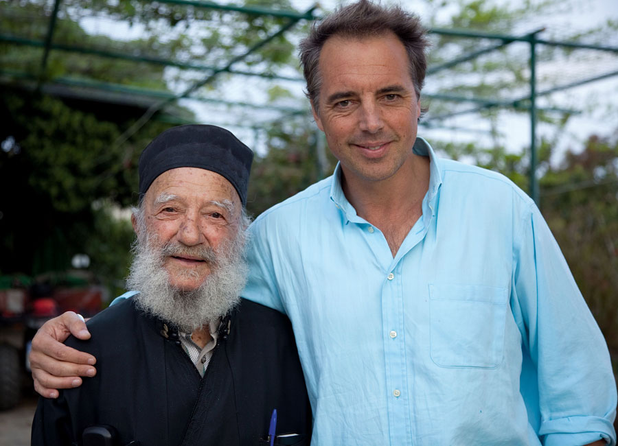 Dan Buettner poses with an older bearded man. Both men are smiling.