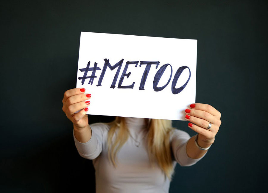 Blonde woman holding up a #MeToo sign over her face.