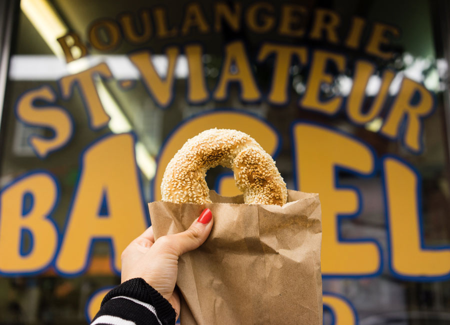 A bagel is held up in front of the store front of St-Viateur bagel shop in Montreal.