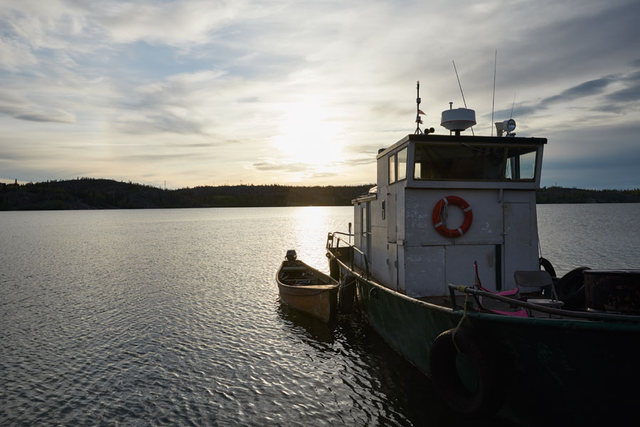 A boat leaving ST. John's Harbour travelling toward the sun on the horizon.