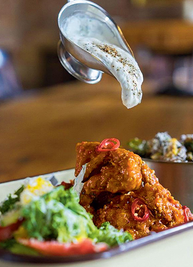 Saucy fried chicken with a cream sauce about to be poured over it.