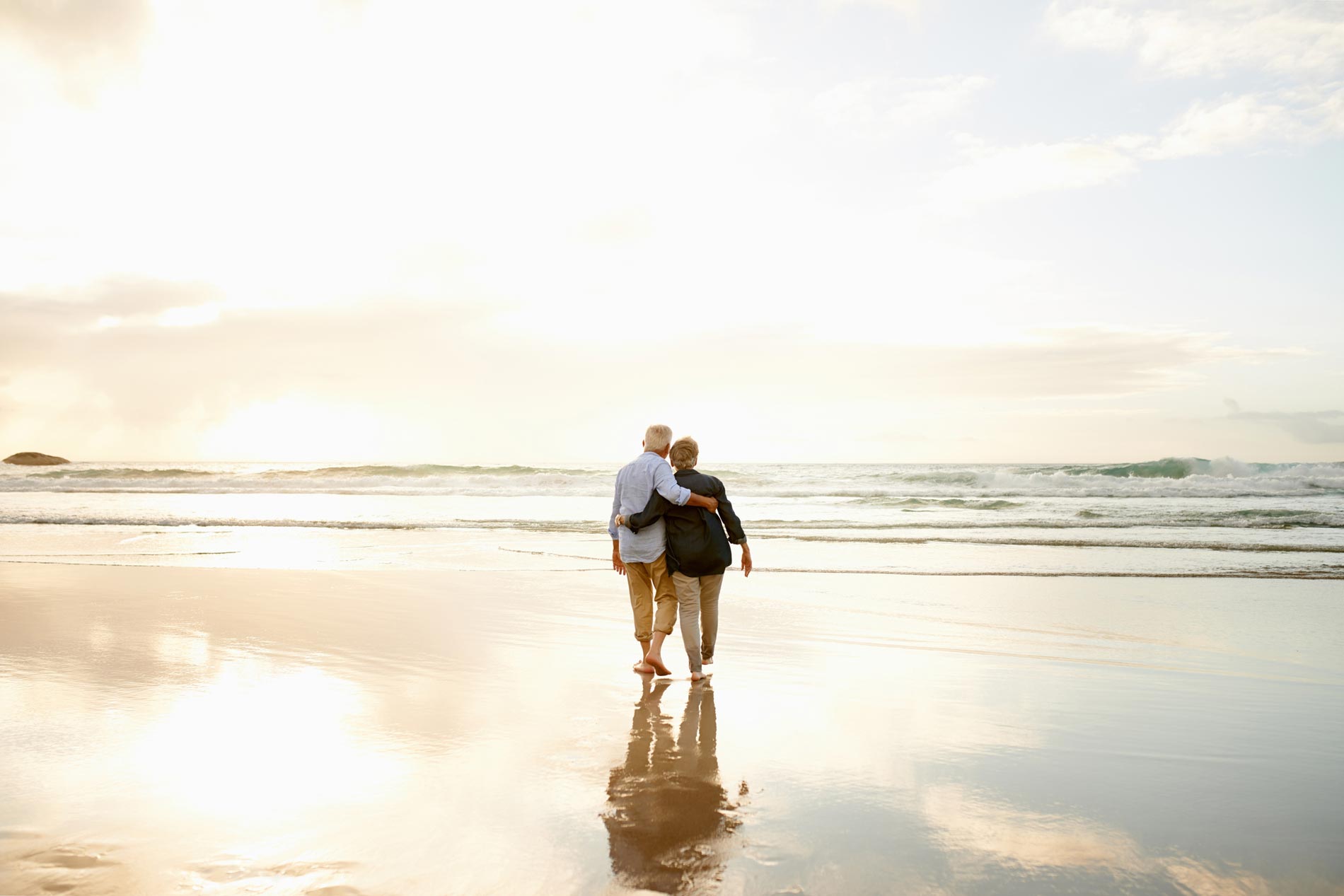 Older couple on the beach, watching the sunset.