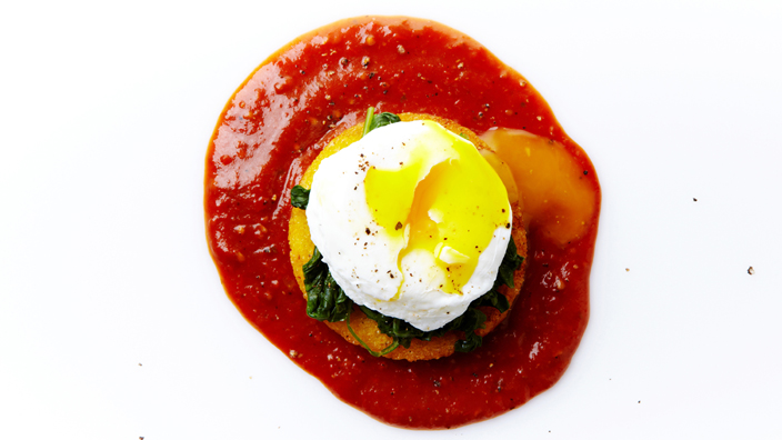 Poached eggs sitting in a puddle of tomato sauce.
