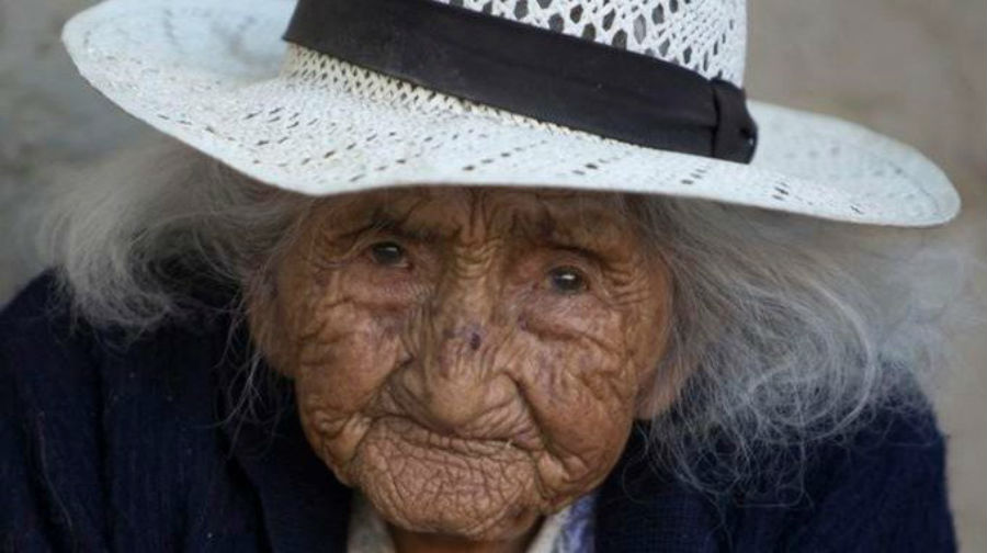 Photo of Bolivian woman believed to be oldest person living wearing a white sunhat and smiling.