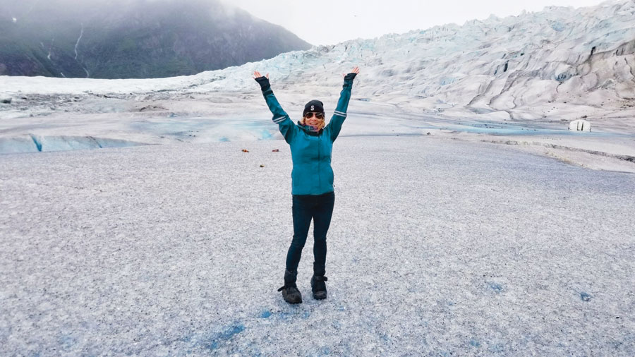Vivian Vassos with her armed stretched over her head as she stands on the solid ice of Mendenhall Glacier.