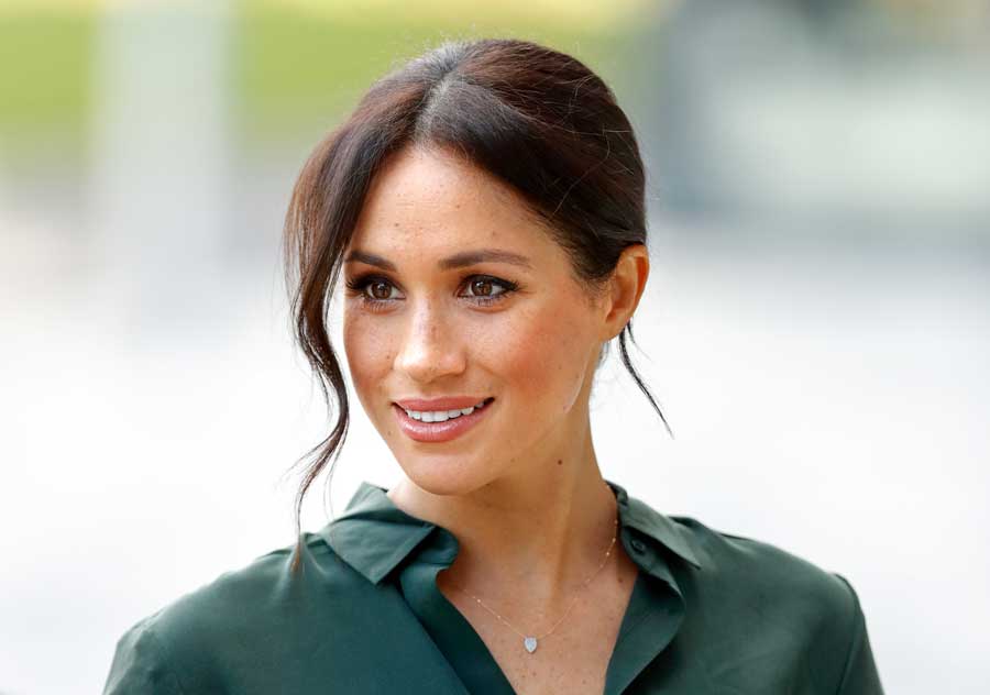 Meghan Duchess of Sussex smiling wearing a green blouse.