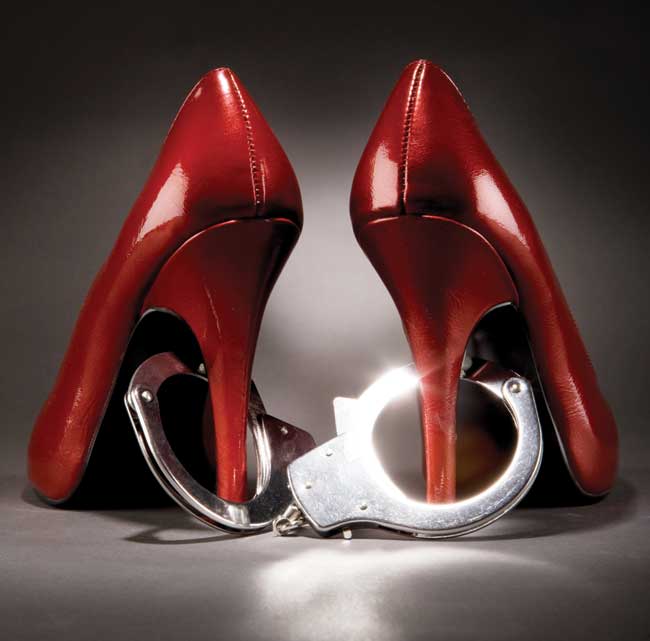 A pair of red high heels with a pair of handcuffs around the heel.