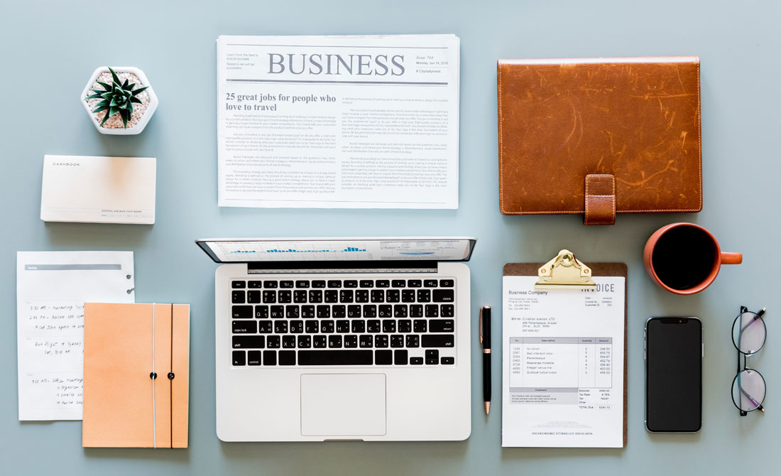 Business desk with computer and newspaper.