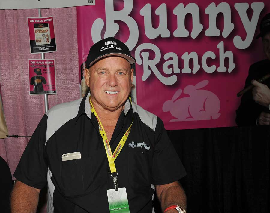 Dennis Hof smiles in front of a promotional sign for his Bunny Ranch brothel.