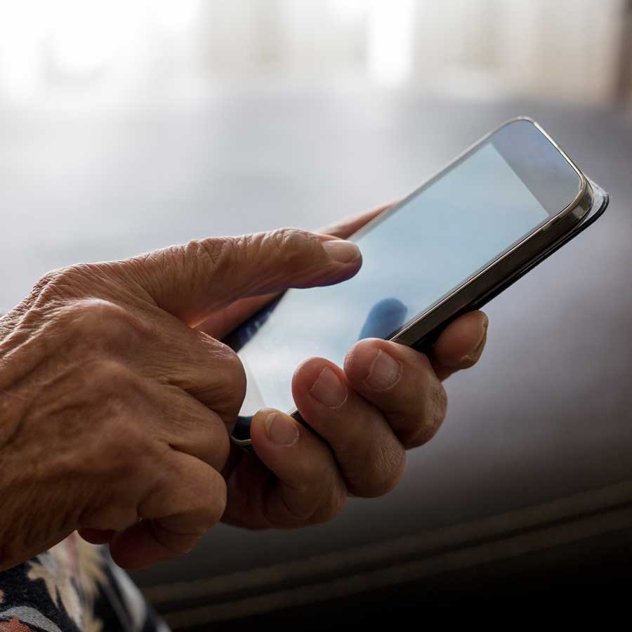 An older persons hands operating a cellphone.