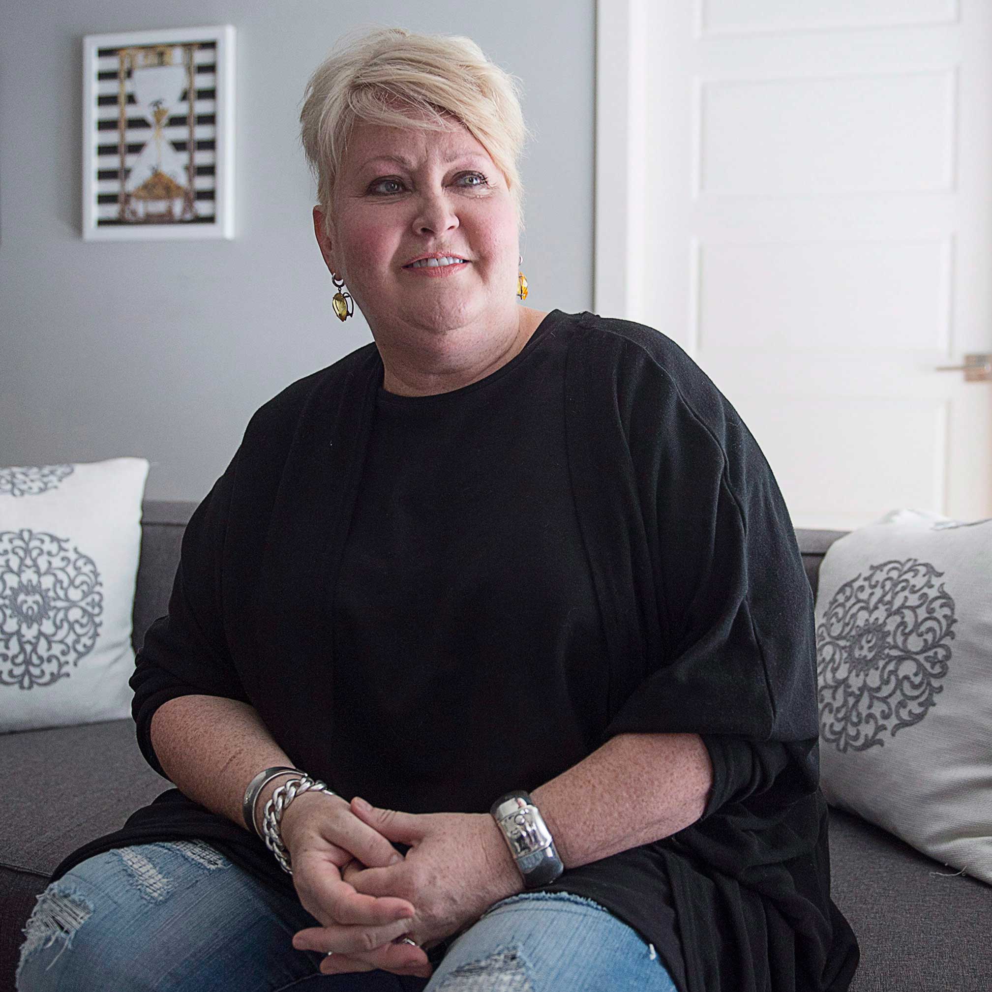 Assisted death advocate Audrey Parker sits on a couch with her hands folded in front of her.