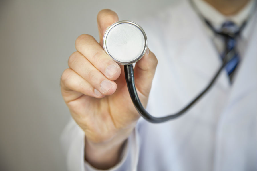 A doctor in a white coat holding up a stethoscope.