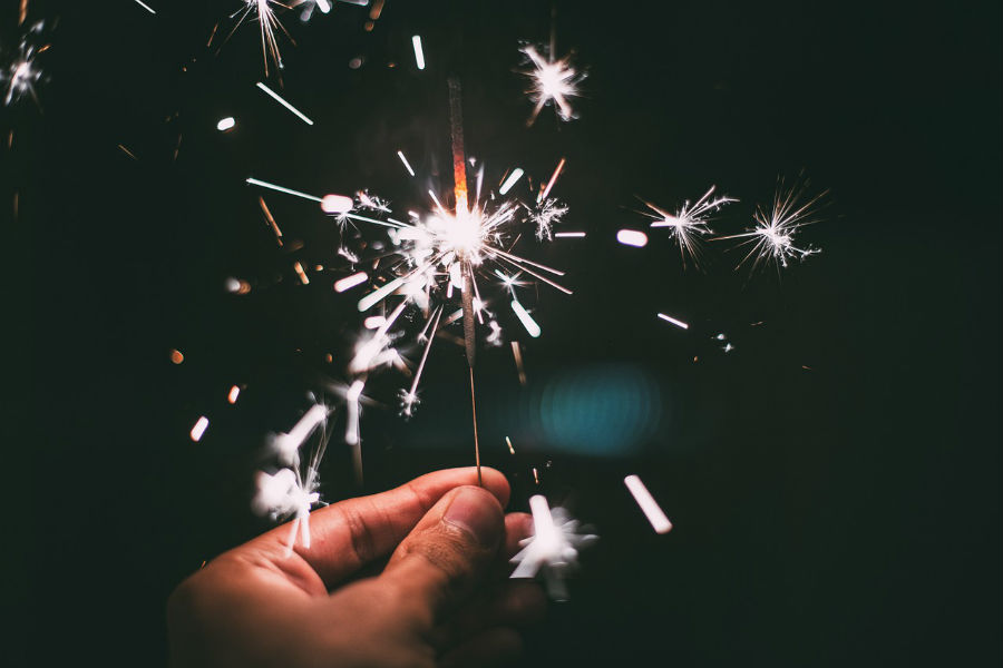 A hand holding a sparkler in the pitch black.